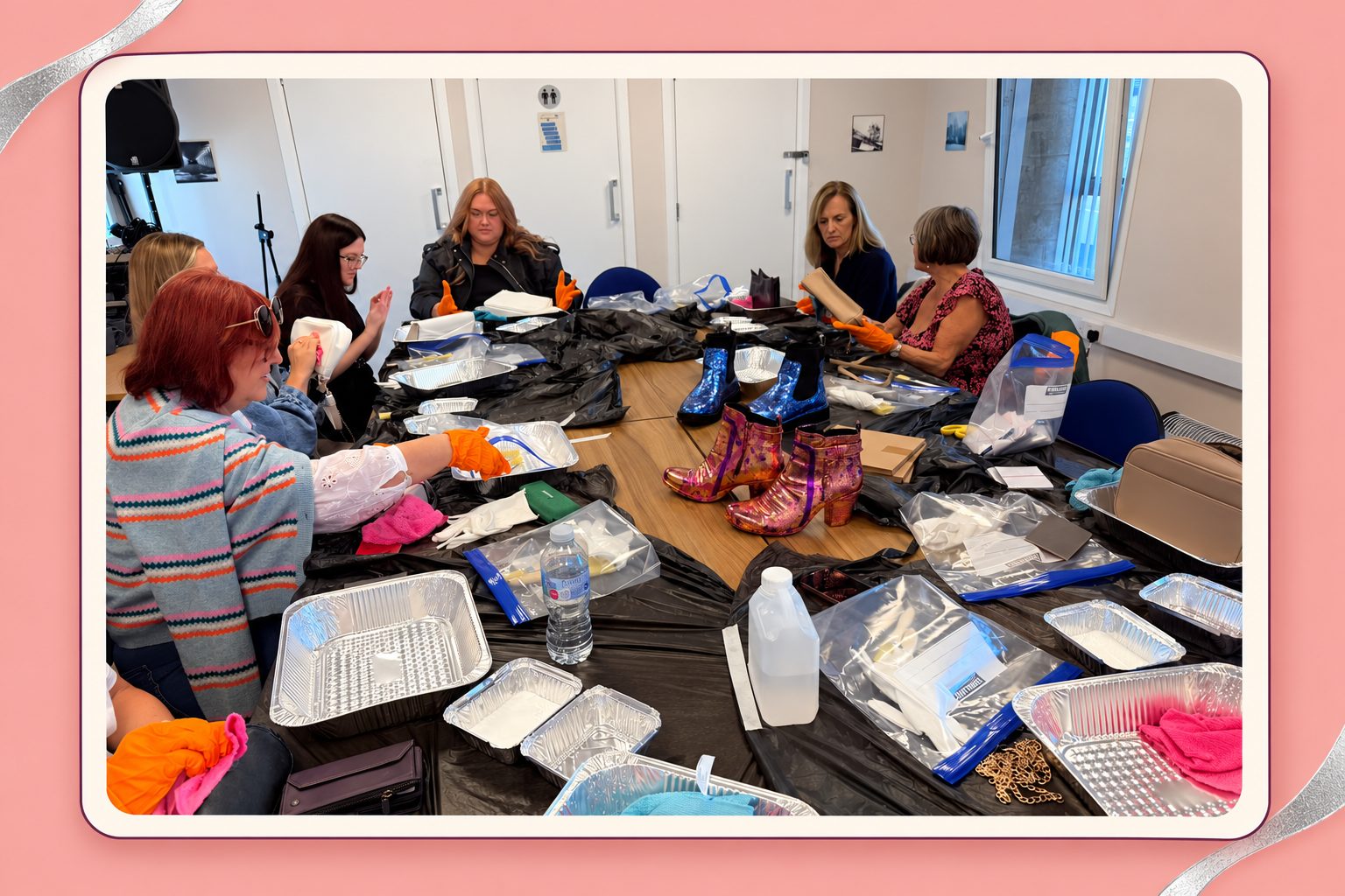 People decorating bags around a table with foil-leaf materials and colourful boots.